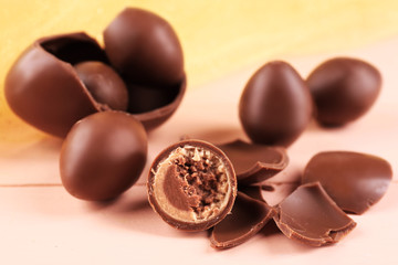 Chocolate Easter eggs on wooden table with tulle, closeup