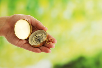 Female hand with compass on bright blurred background