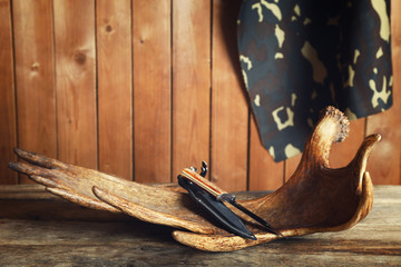Moose antler with hunting knives on wooden background