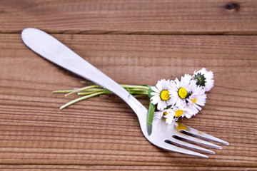 Forks with daisy bouquet on background