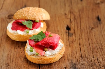 Two sandwiches with cured salmon, cream cheese, parsley, capers