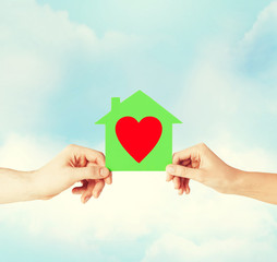 couple hands holding green paper house