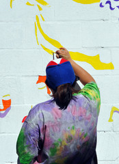 Mujer pintando un mural en la calle - obrazy, fototapety, plakaty