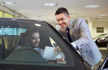 happy man with car dealer in auto show or salon