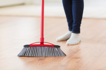 close up of woman legs with broom sweeping floor