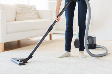 close up of woman legs with vacuum cleaner at home