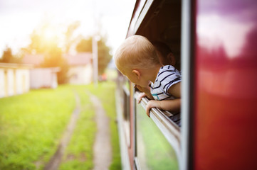 Little boy traveling in train looking outside the window.