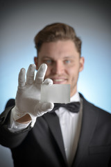 butler wearing white gloves and holding a business card