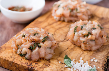 Raw chicken cutlets with herbs on olive wood background