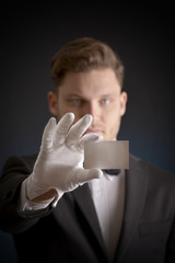 butler wearing white gloves and holding a business card