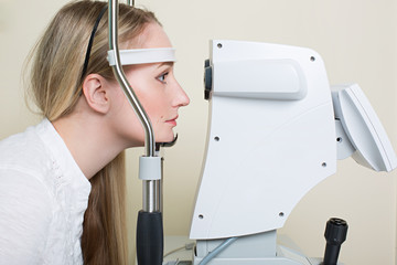 Young woman having her eyes examined by an eye handsome elderly