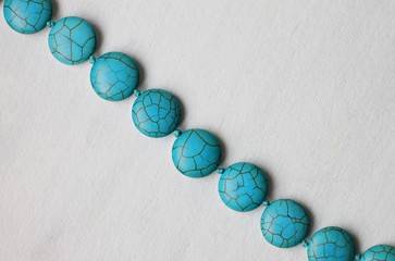 Line of turquoise stone beads bijouterie on white background