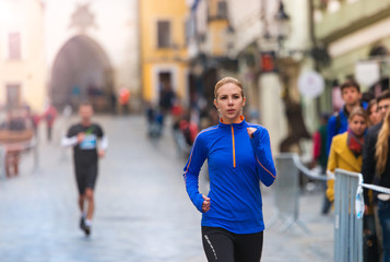 Beautiful young woman running in the city competition with water