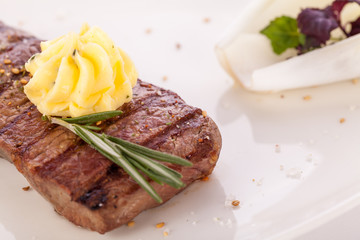 Grilled beef steak topped with butter and rosemary