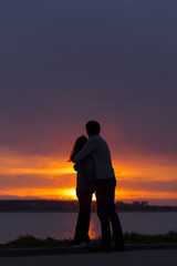 Sillhouette of couple holding together at sunset