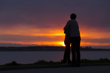 Obraz premium Sillhouette of couple holding together at sunset