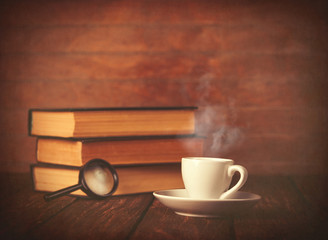 Cup of coffee and book with loupe