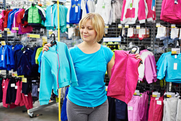 Naklejka na ściany i meble Happy woman shopping for baby sportswear in shop