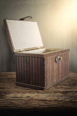 Old wooden chest with open lit on wooden tabletop against grunge