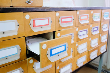 Old wooden card catalog with one opened drawer in library