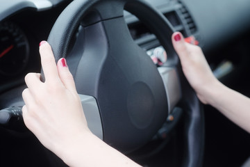 Hands of a woman behind the wheel of car