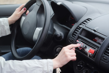 Woman adjusting radio volume in the car.
