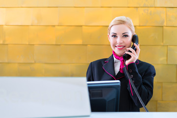 Hotel Rezeptionistin telefoniert mit Gast 