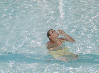 Young adolescent sitting in azure ocean and greedily drinking