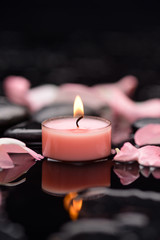 Pink rose petals with candle and therapy stones 