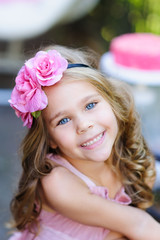portrait of fashion little girl with curly hair and pink flower