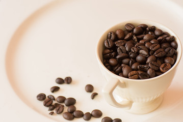 Coffee beans in cup on white plate.