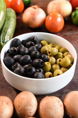 green and black olives in white bowl and ingredients for pizza