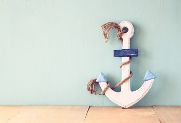 old nautical anchor on wooden table over wooden aqua background © tomertu