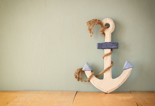 old nautical anchor on wooden table over wooden aqua background