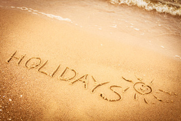 The word holidays written in the sand on a beach