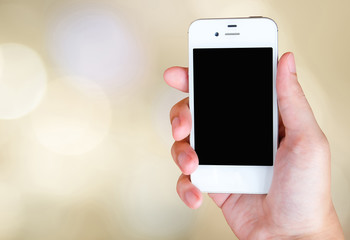 Smart phone in hand on bokeh background