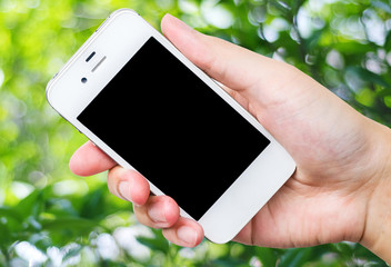 Smart phone in hand on blur tree with bokeh background