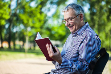 Senior man reading a book in park