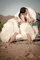 Young happy bridal couple sitting outdoors flirting and kissing