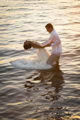 Silhouette of wedding couple dancing in water at sunset