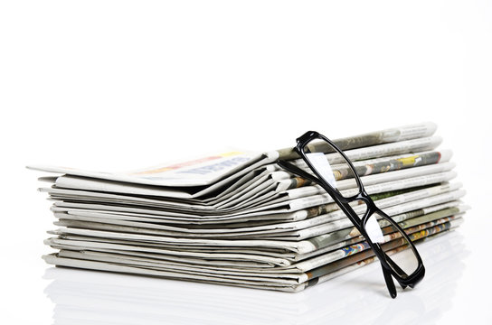 glasses lean on newspapers against white background
