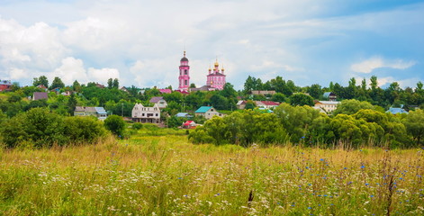Fototapeta na wymiar Russian landscape with church, meadow flowers and clouds.