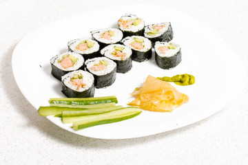 Homemade sushi in a white plate with wasabi and ginger