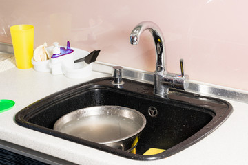 Black sink with dish washer and yellow sponge