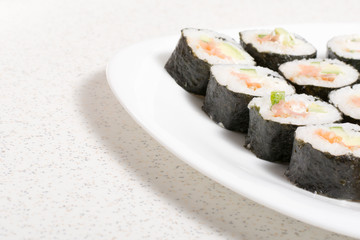 Homemade sushi in a white plate with wasabi and ginger