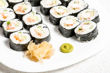 Homemade sushi in a white plate with wasabi and ginger