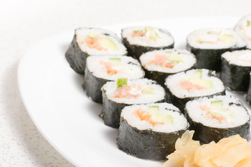 Homemade sushi in a white plate with wasabi and ginger