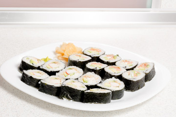 Homemade sushi in a white plate with wasabi and ginger
