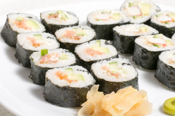 Homemade sushi in a white plate with wasabi and ginger