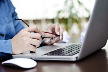 a young woman holding her glasses while working on computer